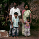 Jagada Guru, whose kothi name is Arundhati, poses for a portrait with his wife and children outside of their house in Devanipattinam.